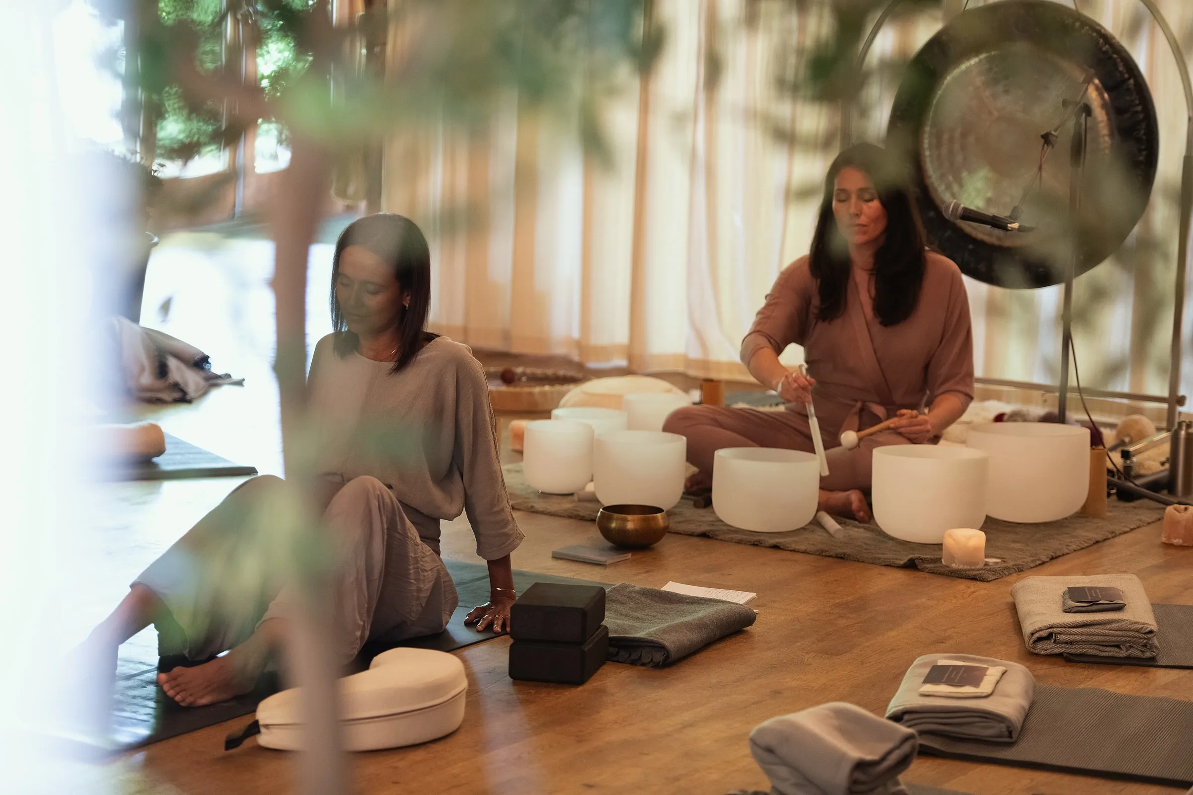Two women leading a sound bath with crystal bowls and a gong on the barn floor