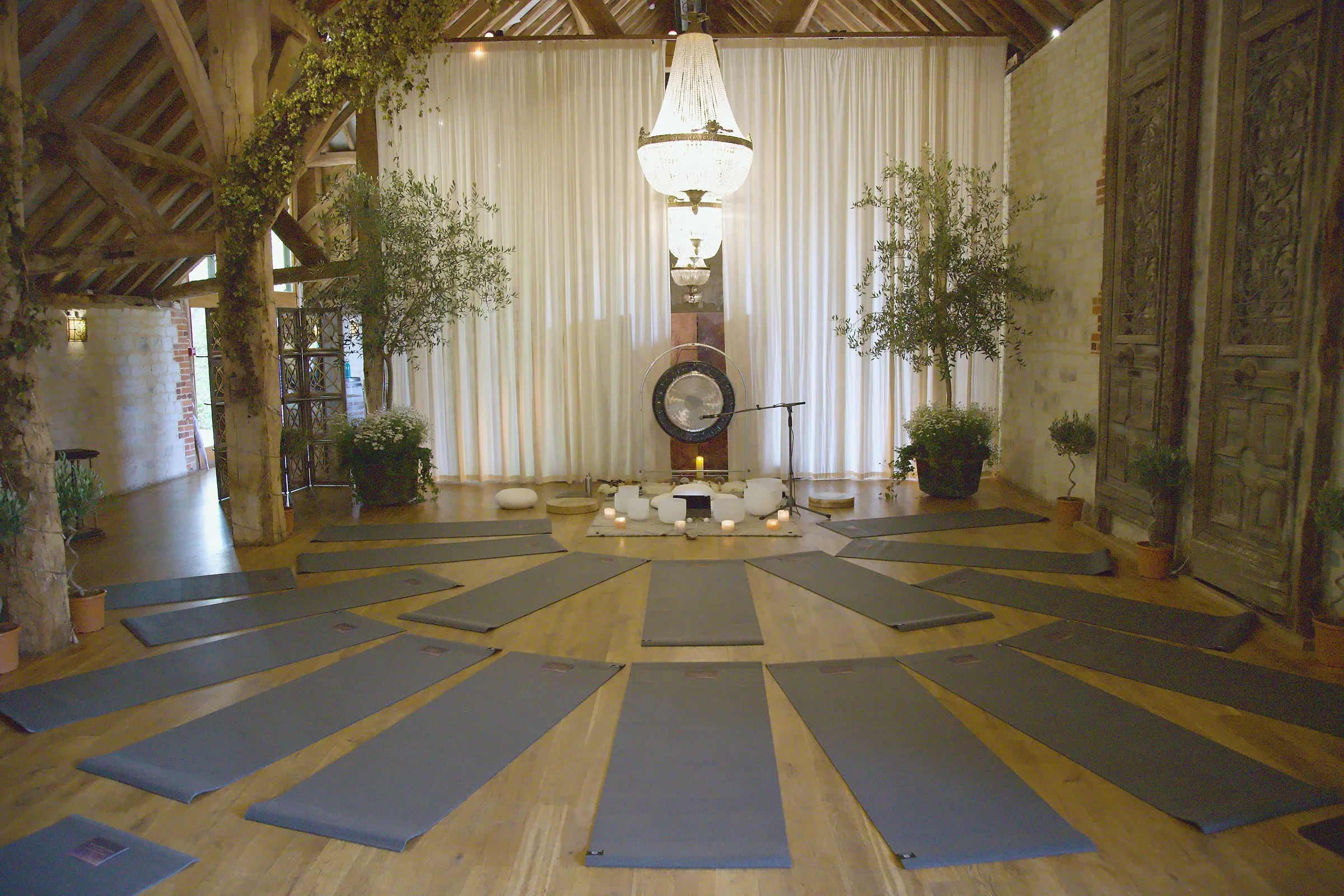 Yoga mats laid in a circle around a gong and singing bowls in the barn